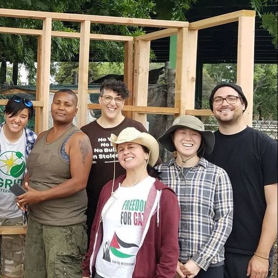Group of 10 cohort members posing around the frame they just built that will become a potting shed for Sogorea Te Land Trust. One person is holding a hammer.