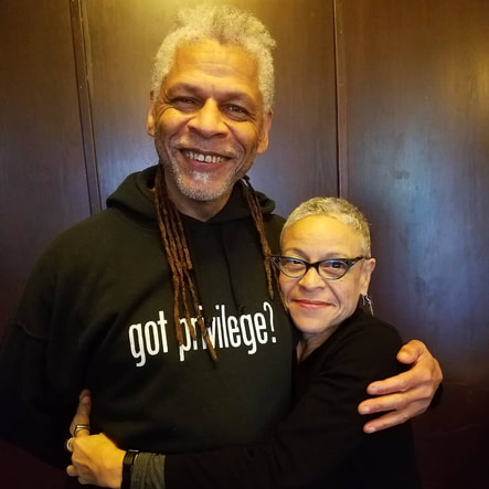 Photo of facilitators Victor and Lynice embracing and smiling into the camera. Victor's hoodie reads, 